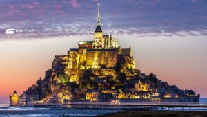 Mont Saint-Michel illuminato al tramonto sulla baia, Bretagna e Normandia in un tour tra abbazie e coste
