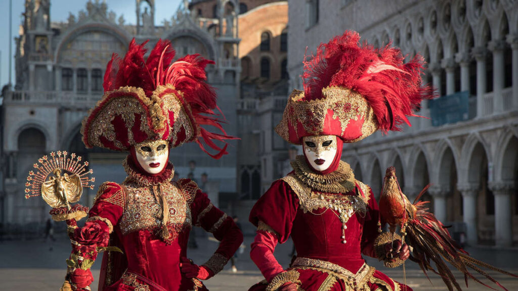 Due persone in costumi rossi e maschere davanti alla Basilica di San Marco a Venezia