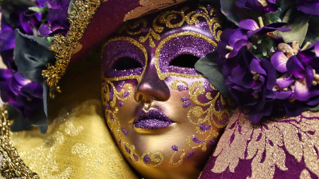 Maschera viola e dorata con decorazioni floreali al Carnevale di Venezia