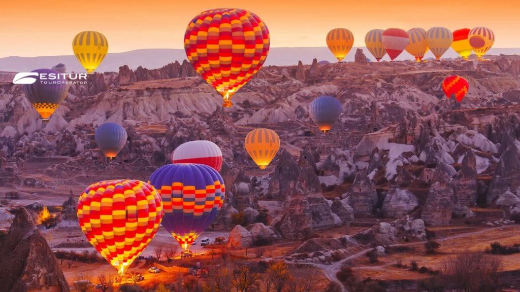 Mongolfiere colorate sorvolano le valli rocciose all’alba, esperienza di Mongolfiera in Cappadocia durante un viaggio