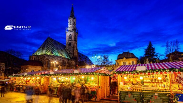 Bancarelle illuminate sotto il campanile di Bolzano, Mercatini di Natale in Italia per un viaggio d’inverno
